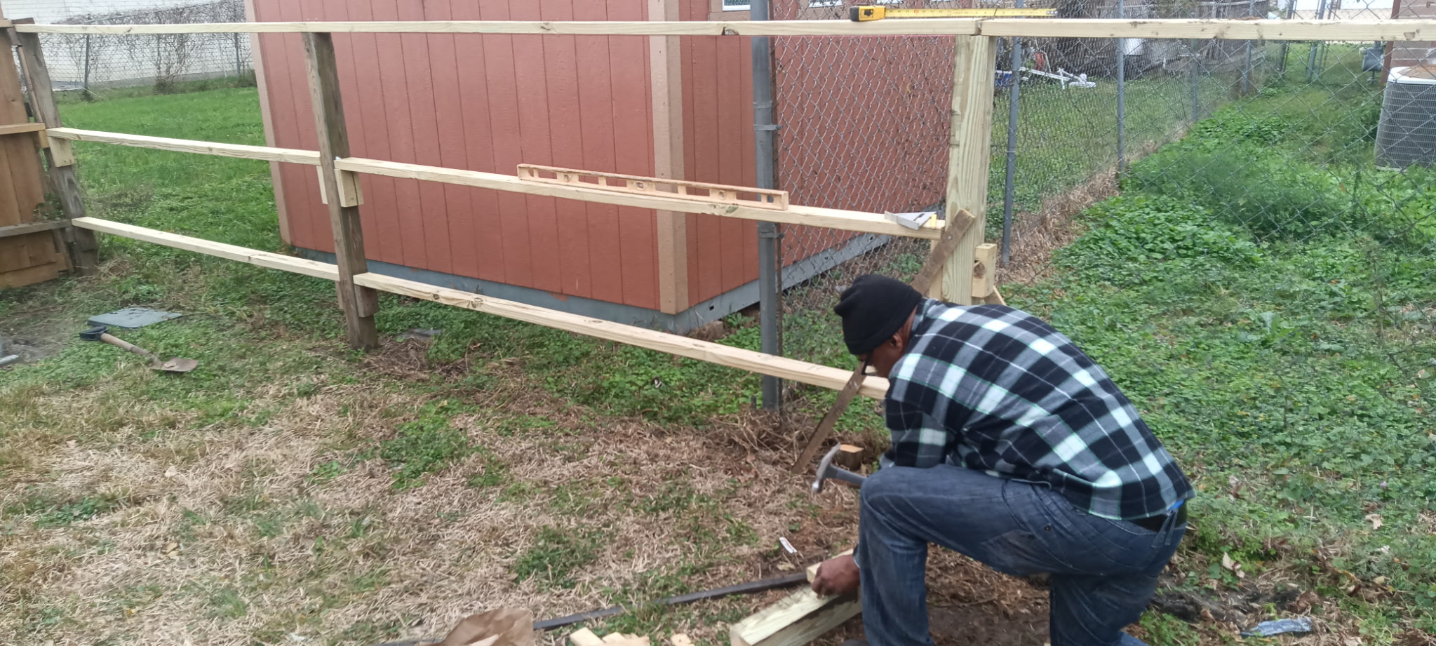 Fence installer carefully building horizontal rails on set posts